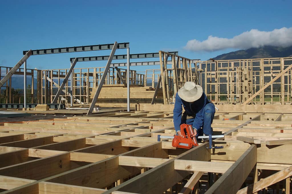 A builder contractor working outdoors on a new wooden frame building in New Zealand