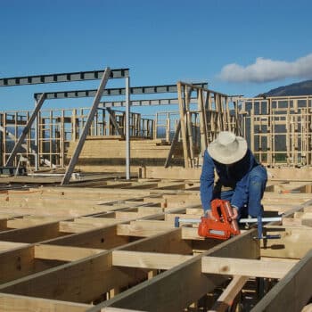 A builder contractor working outdoors on a new wooden frame building in New Zealand